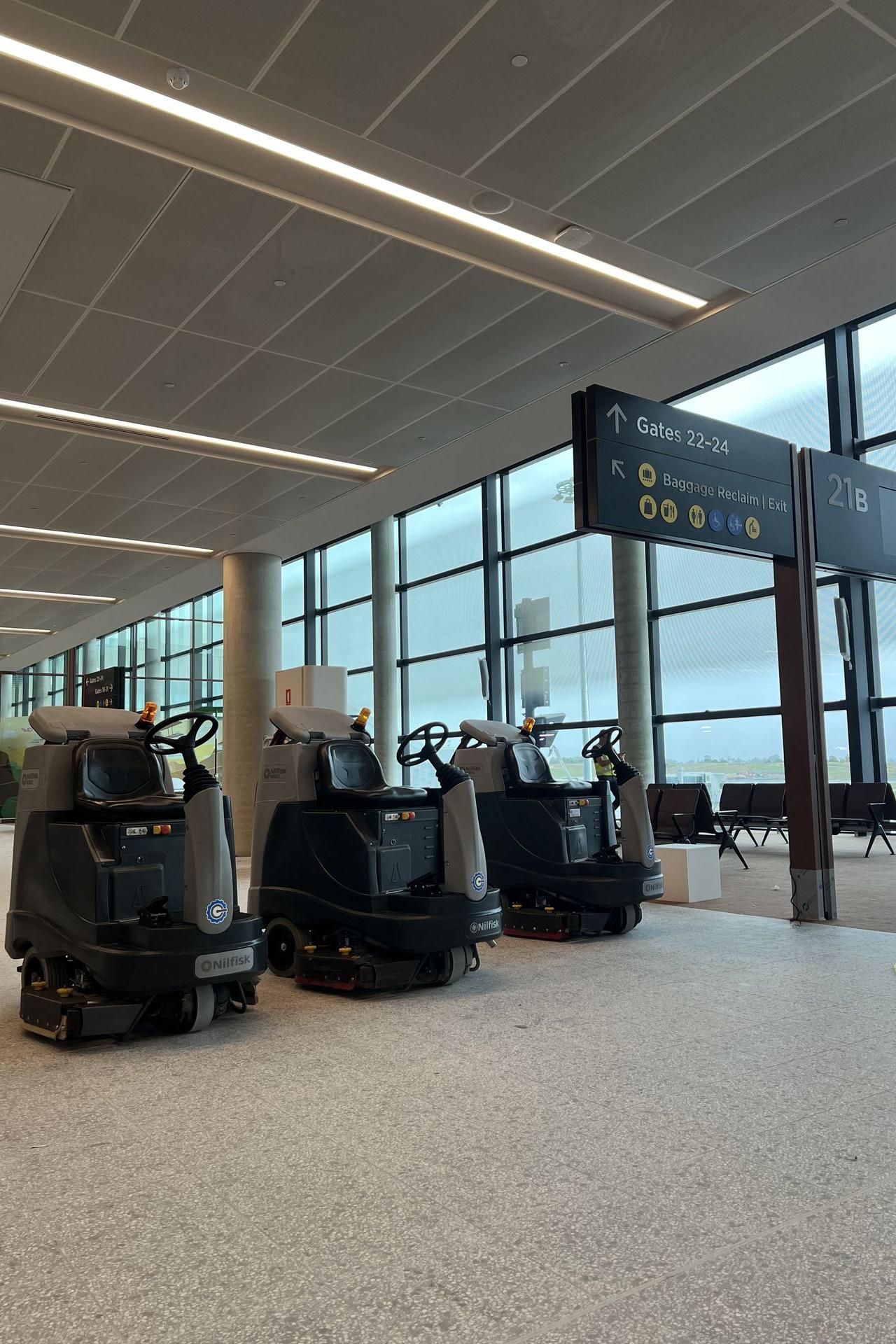 Commercial floor scrubbers cleaning terminal floors inside an airport facility.